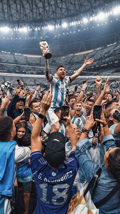 a man holding up a trophy while surrounded by fans