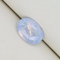 an oval shaped blue stone sitting on top of a white cloth covered surface with light colored fabric