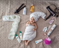 a baby laying on top of a bed next to personal care items