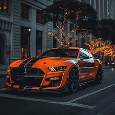 an orange sports car parked on the side of the road in front of some buildings