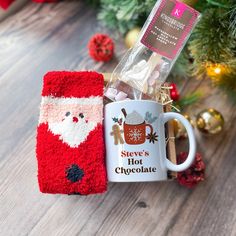 a mug with a santa clause sweater on it next to a christmas ornament