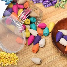 colorful beads are scattered around a wooden bowl