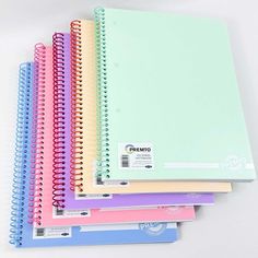 five spiral bound notebooks lined up on top of each other, with different colored pages