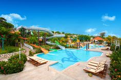 an outdoor swimming pool with slides and water park in the backround, surrounded by lush greenery