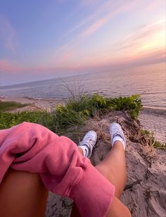 a person sitting on top of a sandy beach next to the ocean with their feet in the sand