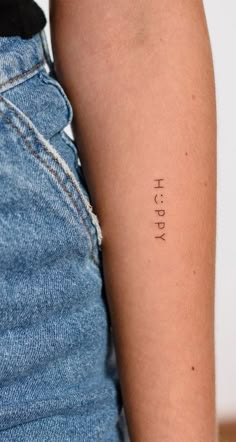 a woman's arm with the word happy tattooed on her left arm, in black ink