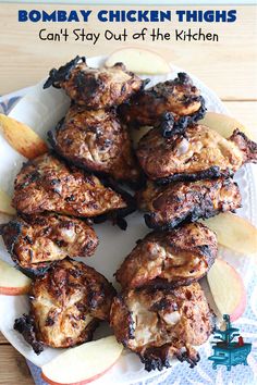 some chicken thighs are on a plate with apples