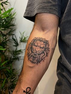 a man's arm with a lion tattoo on it and an egyptian cross in the middle