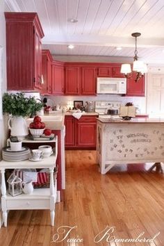 a kitchen with red cabinets and white appliances in the center is decorated with christmas decorations