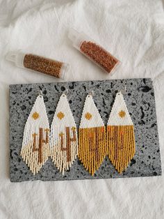 three pieces of beaded art are displayed on a white towel next to some beads