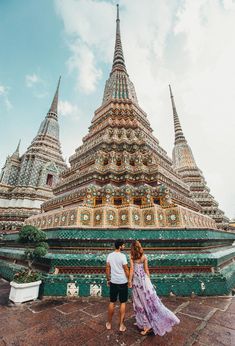 a man and woman standing in front of a building with many spires on it