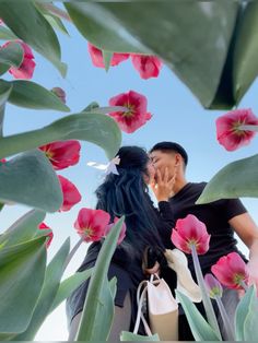 a man and woman kissing in front of pink flowers