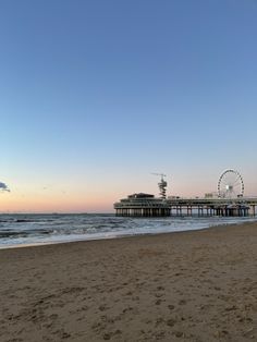 a pier on the beach with ferris wheel in the background