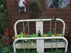 an old bed frame with flowers growing in it