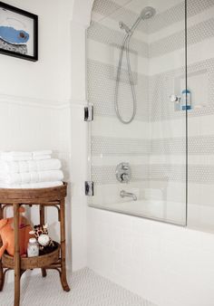 a bathroom with a stand up shower and white towels on the shelf next to it