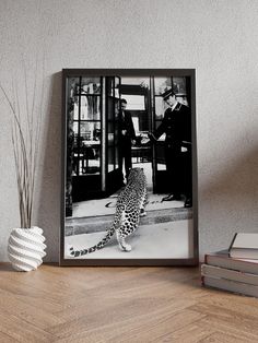 a black and white photo of a leopard in front of a door with two men standing behind it