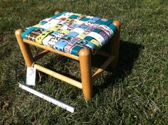 a small wooden stool sitting on top of a grass covered field next to a ruler