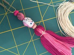 two tassels with beads on them sitting on a table next to some string