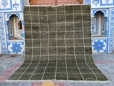 an area rug in front of a building with blue and white tiles on the walls