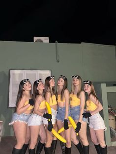 four young women in short shorts and yellow shirts are posing for a photo with bananas