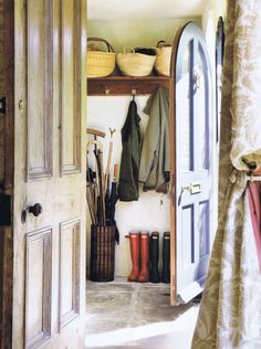 an open door leading into a room with boots and umbrellas on the shelf next to it