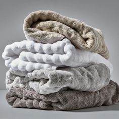 several folded towels stacked on top of each other in different colors and sizes, all piled together