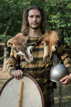 a man with long hair holding a cat on his shoulder while standing next to a drum