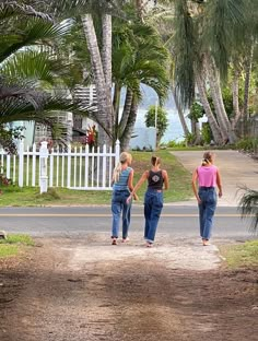 three women walking down the road in front of palm trees