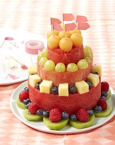 a watermelon and kiwi fruit cake on a white plate with pink checkered tablecloth