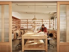 a woman working in a woodworking shop with lots of shelves and drawers on the wall