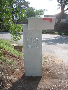 a cement marker with the number twelve eleven on it in front of a road and trees