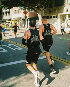 two men running down the street in shorts and vests with their backs turned towards each other