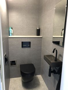 a black toilet sitting in a bathroom next to a sink