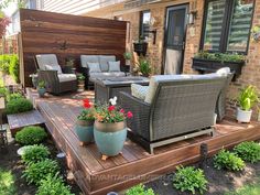 a deck with chairs and potted plants in front of it on the side of a house