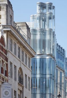 a tall glass building sitting on the side of a street next to other large buildings