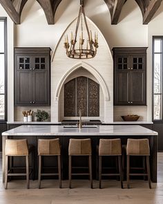 a large kitchen with black cabinets and white marble counter tops, an arched doorway leading to the dining room