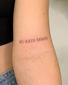 a woman's arm with roman numerals tattoo on the back of her left arm