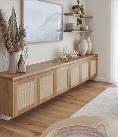 a living room filled with lots of furniture next to a wall mounted art piece on top of a wooden shelf