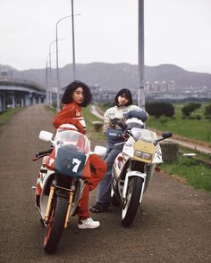 two people sitting on motorcycles next to each other