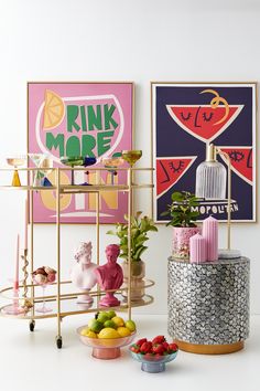 various items are arranged on a shelf in front of posters and other art work,