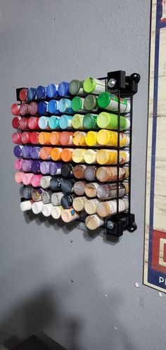 there are many different colored paints on the wall and one is hanging in front of it