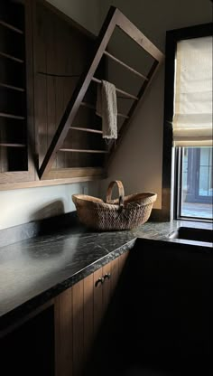 a basket sitting on top of a counter next to a window with blinds in it