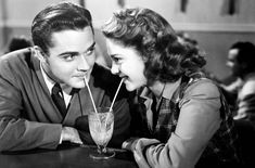 a man and woman sitting at a table with a drink