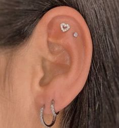 a woman wearing an ear piercing with two hearts on it