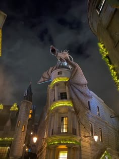 a large building with lights on it and a dragon statue in the middle of the front