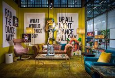 a living room filled with lots of furniture next to large posters on the wall and floor