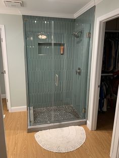 a walk in shower sitting inside of a bathroom next to a door and wooden floor