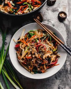 a white bowl filled with vegetables and chopsticks