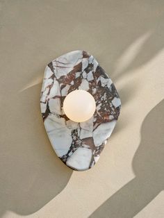 a white and black marble plate with a light on it's side in the middle