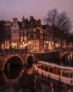 a boat is on the water in front of some buildings with lights all around it